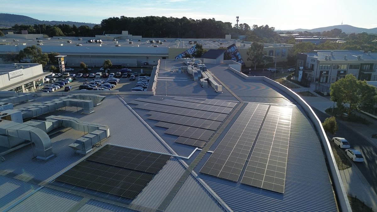 Wide aerial view of commercial rooftop solar panels