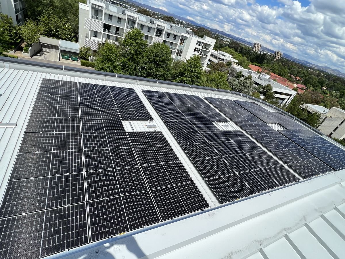 Rooftop solar panel array beside apartment buildings